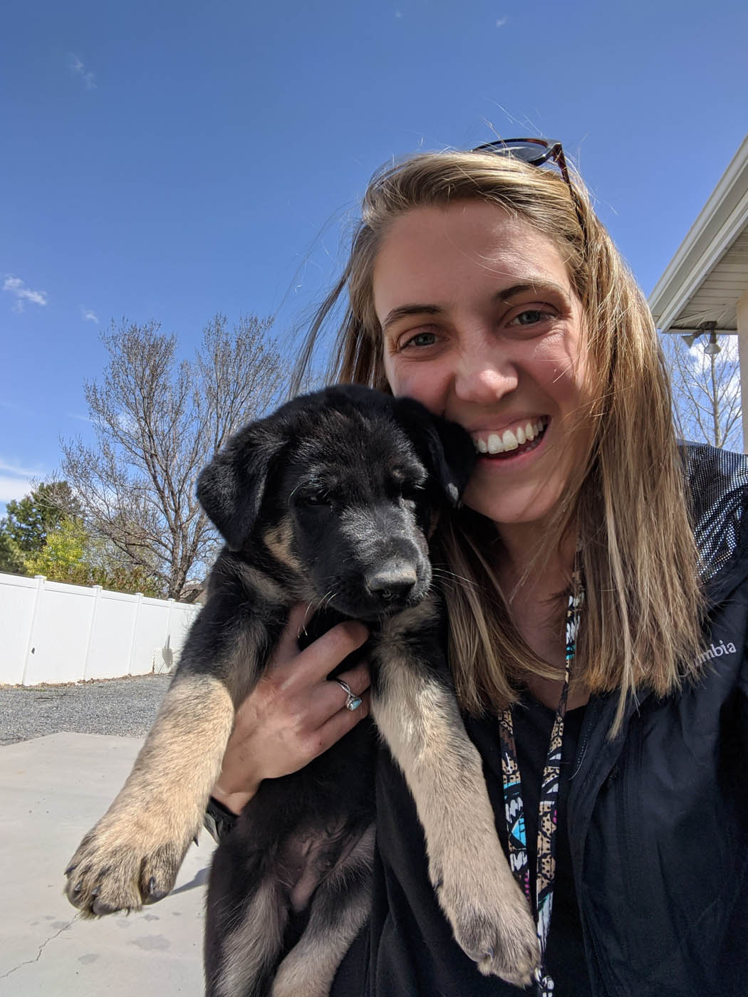 An image of a girl holding her puppy at home - discover the benefits of Boston in house puppy training with Dog Training Elite.