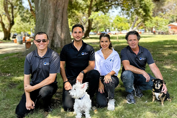 A well trained dog and their owner posing in front of a Dog Training Elite wall.