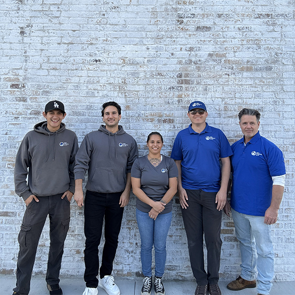 A well trained dog and their owner posing in front of a Dog Training Elite wall.